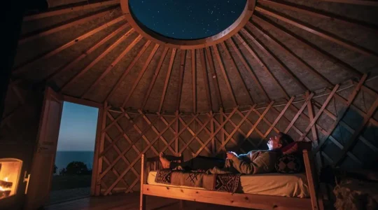 Intérieur chaleureux d'une yourte la nuit, avec vue sur le ciel étoilé à travers l'ouverture zénithale, non loin de la côte basque