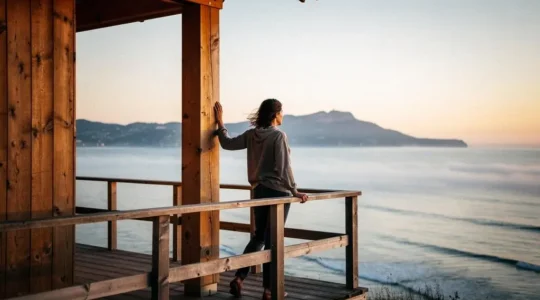 Silhouette au lever du jour face à l'océan Atlantique depuis un hébergement insolite du Pays Basque, symbolisant la régénération mentale par une expérience originale